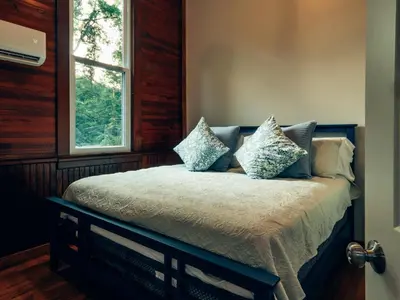 a bedroom with a bed with pillows and a window at Corton Lodge on the Elk River - Riverview Suite