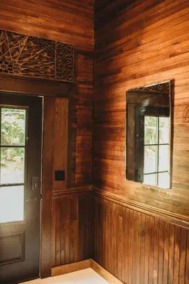 a room with wooden walls with a door and a window at Corton Lodge on the Elk River - Riverview Suite