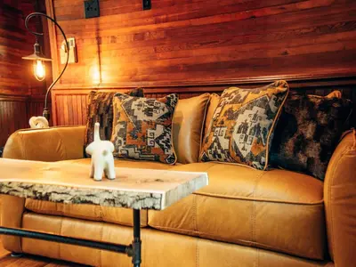 a brown leather couch with pillows on a table at Corton Lodge on the Elk River - Riverview Suite