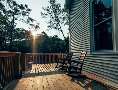 two chairs sitting on a porch with the sun shining at Corton Lodge on the Elk River - Riverview Suite