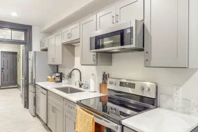 a kitchen with white cabinets and stainless steel appliances at Cincy Apt 1 Mi to Findlay Market, 2 Mi to Downtown in Cincinnati