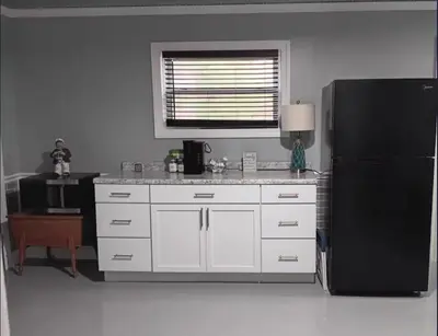 a kitchen with white cabinets and a black refrigerator at The Reel Freedom Cottage at Leesville Lake in Carrollton