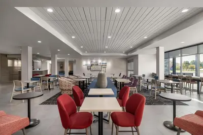 a dining room with tables and chairs and windows at Home2 Suites By Hilton Muncie in Muncie