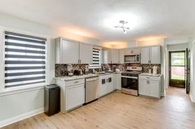 a large kitchen with white cabinets and wooden floors at 3 Mi to Dtwn Youngstown and YSU Family Home with Yard in Youngstown