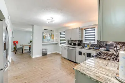 a kitchen with white cabinets and a wooden floor at 3 Mi to Dtwn Youngstown and YSU Family Home with Yard in Youngstown