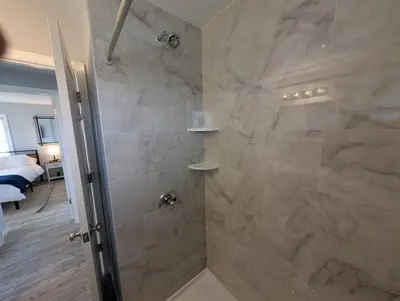 a bathroom with a walk in shower next to a bed at Relaxing River View Stay Renovated 3BR Home in Fremont