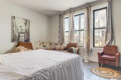 a bedroom with a bed and a couch and windows at Walkable Apt in York St Historic District in Newport