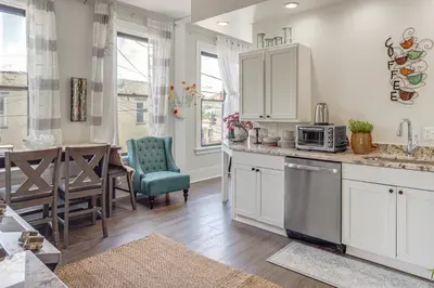 a kitchen with white cabinets and a dining room at Walkable Apt in York St Historic District in Newport