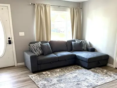 a blue couch in a living room with a window at Private Home - Entire House - Ranch - Hot Tub - Pets Welcome - 2 King Beds - Kids Welcome - Fenced Yard - Free Wifi - Quiet Neighborhood in Columbus