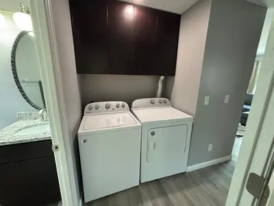 a washer and dryer in a bathroom with a mirror at Private Home - Entire House - Ranch - Hot Tub - Pets Welcome - 2 King Beds - Kids Welcome - Fenced Yard - Free Wifi - Quiet Neighborhood in Columbus