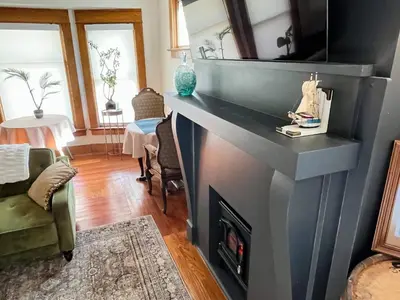 a living room with a fireplace with a tv above it at Fiesinger House - Private 1-bd unit, Historic Home Downtown Sandusky in Sandusky