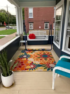 a rug on a porch with a swing at Fiesinger House - Private 1-bd unit, Historic Home Downtown Sandusky in Sandusky