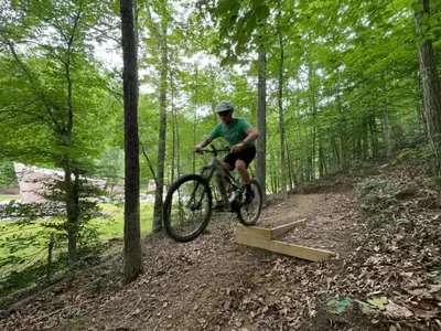 a man riding a bike on a trail in the woods at Safari Tent Glamping in Kentucky with AC and Access to Biking Trails in Grayson