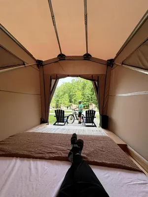 a person laying on a bed in a tent at Safari Tent Glamping in Kentucky with AC and Access to Biking Trails in Grayson