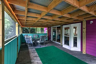 a covered porch with a table and chairs and a green rug at Resort Cabin 1 Mi to Middle Bass Island State Park in Middle Bass