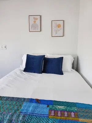 a white bed with blue pillows and a blanket on it at Luxe Mt Adams Lookout in Cincinnati