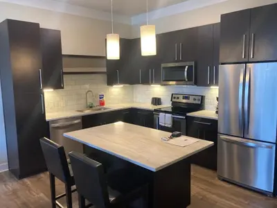 a kitchen with black cabinets and a kitchen island with a refrigerator at Beautiful in Beachwood in Beachwood