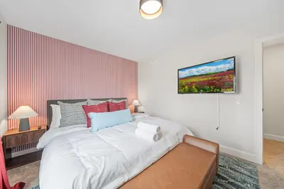 a bedroom with a large white bed with a tv on the wall at Hot Tub - Mins to Short North - Retro Game Room in Columbus