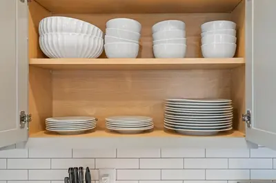 a cupboard filled with white plates and dishes at Hot Tub - Mins to Short North - Retro Game Room in Columbus