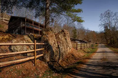 a house on a hill next to a fence at Ohio Starlight Glamping Cabins - A Peaceful Woodland Retreat