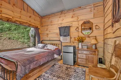 a bedroom in a log cabin with a bed and a window at Ohio Starlight Glamping Cabins - A Peaceful Woodland Retreat