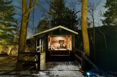 a bed in a tiny house in the woods at Ohio Starlight Glamping Cabins - A Peaceful Woodland Retreat