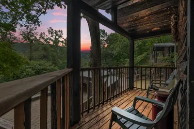 a deck with two chairs and a view of the mountains at Ohio Starlight Glamping Cabins - A Peaceful Woodland Retreat