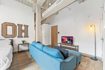 a living room with a blue couch and a tv at Studio at Superior l Downtown l Parking l Café in Cleveland