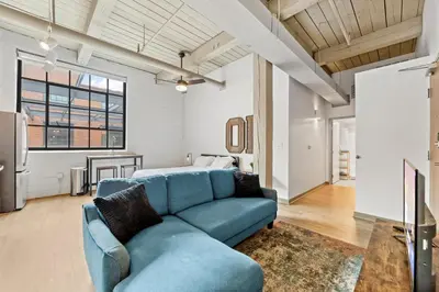 a living room with a blue couch and a bed at Studio at Superior l Downtown l Parking l Café in Cleveland