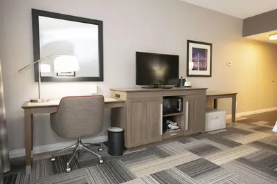 a room with a desk with a television and a chair at Hampton Inn Toledo Oregon in Oregon