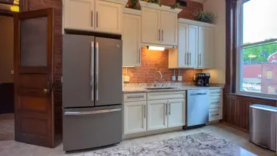 a kitchen with white cabinets and a stainless steel refrigerator at Court St Suite in Clarksburg