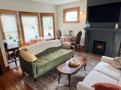 a living room with a green couch and a fireplace at Fiesinger House - Entire Historic Home, Downtown Sandusky in Sandusky