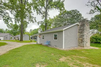 a gray house with a stone chimney and a yard at Boat Dock Couples Grand Lake Getaway!