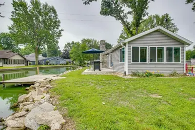 a small house with an umbrella next to a body of water at Grand Lake Cabin with Private Dock in St Marys!