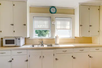 a kitchen with a sink and a microwave and two windows at Walk to Private Beach Lake Erie Retreat with Yard! in Huron