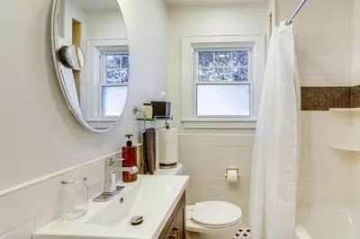 a white bathroom with a sink and a mirror at Walk to Private Beach Lake Erie Retreat with Yard! in Huron