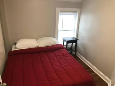a bed with a red blanket in a room with a window at The House Hotels - W45th Backhouse - Ohio City in Cleveland