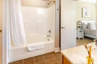 a bathroom with a tub and a shower and a sink at The Penny Lane Suite in Akron