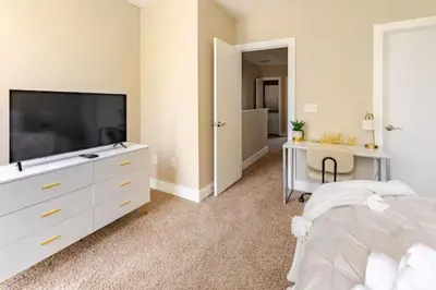 a bedroom with a white dresser and a tv at The Penny Lane Suite in Akron