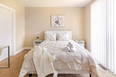 a white bedroom with a large bed with white sheets at The Penny Lane Suite in Akron