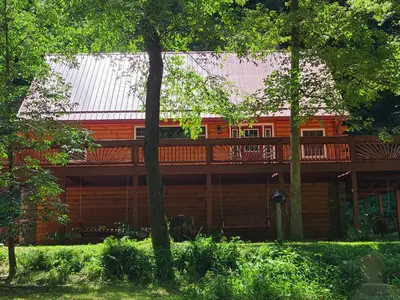 a house with a deck in the middle of trees at A Birds Eye View Cabin Rentals in Logan