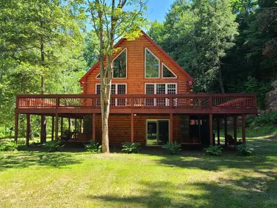 a log cabin with a large deck in the woods at A Birds Eye View Cabin Rentals in Logan