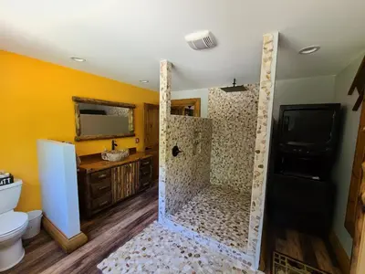 a bathroom with a shower with a toilet and a television at A Birds Eye View Cabin Rentals in Logan