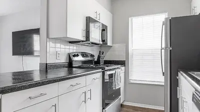 a kitchen with white cabinets and a black refrigerator at Landing Chic 1BD Clubhouse Gym in Dayton