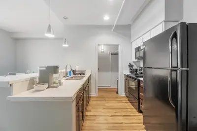 a kitchen with a stainless steel refrigerator and wooden floors at Spacious DT Condo l Free Parking l Fast Wi-Fi in Cleveland