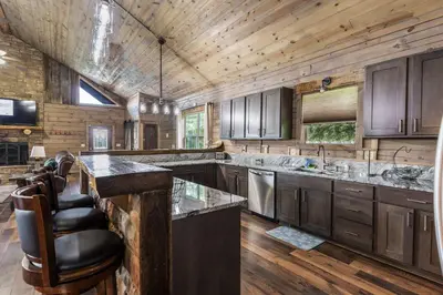 a large kitchen with wooden walls and wooden floors at Serenity Ridge 6 Br Sleeps 16 Pool Hot Tub in Creola