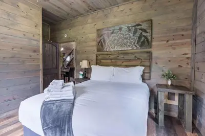 a bedroom with a large bed in a wooden wall at Serenity Ridge 6 Br Sleeps 16 Pool Hot Tub in Creola