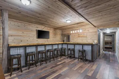 a bar with stools in a room with wooden walls at Serenity Ridge 6 Br Sleeps 16 Pool Hot Tub in Creola