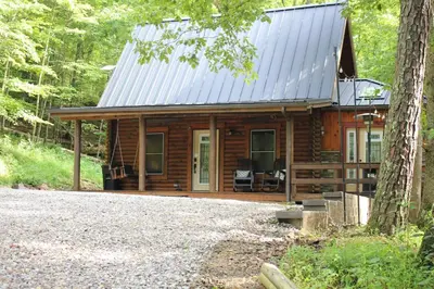 a log cabin in the woods with a porch at Diamond Creek | Sleeps up to 6 in Gallipolis