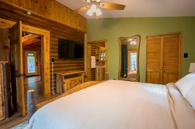 a bedroom with a bed in a room with wooden walls at Diamond Creek | Sleeps up to 6 in Gallipolis
